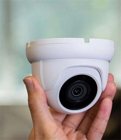 Hand holding a modern CCTV camera for indoor or outdoor security installation